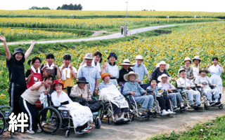 入居者が車いすで花畑を鑑賞する野外レクリエーション活動